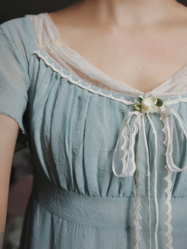 Close-up of dusty blue cottagecore victorian dress with ivory lace neckline and floral ribbon detail