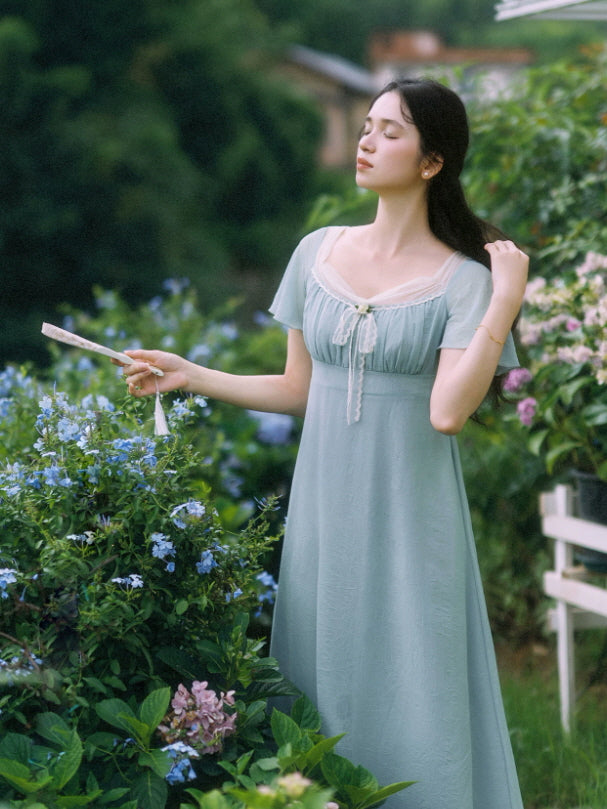 Romantic blue summer fairytale dress with flutter sleeves among blooming garden flowers