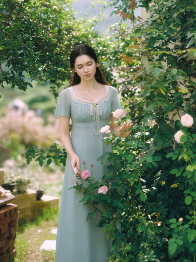 Dusty blue romantic maxi dress with lace neckline in a blooming rose garden
