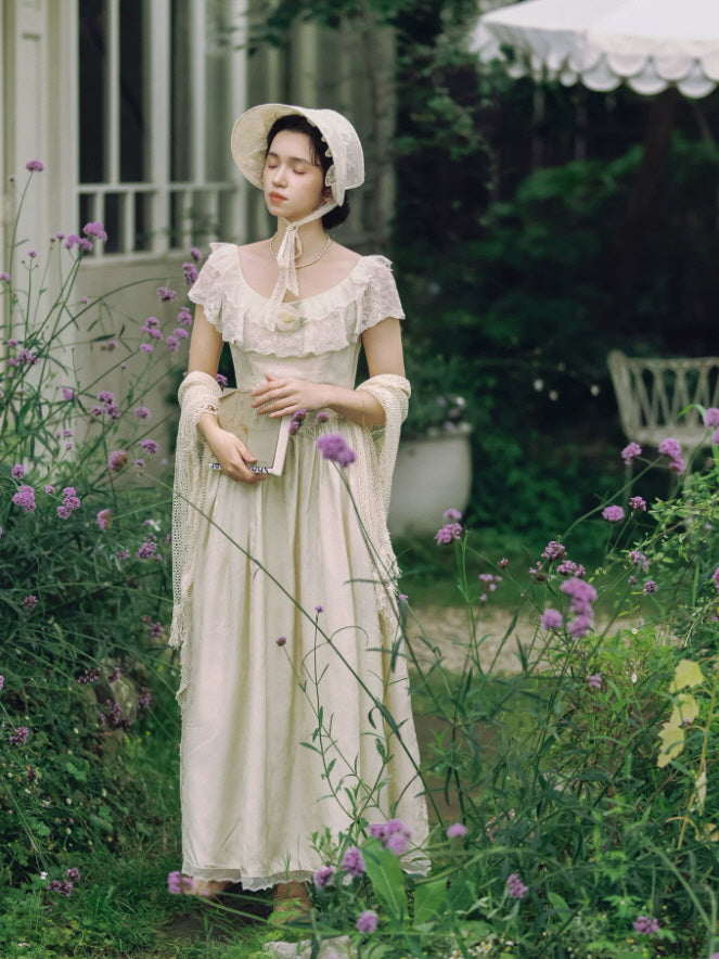 Ivory vintage cottagecore dress styled with lace bonnet and shawl in a dreamy flower garden