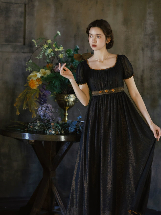 Vintage inspired black maxi dress with orange trimmed neckline, floral waist embellishment and graceful full length skirt