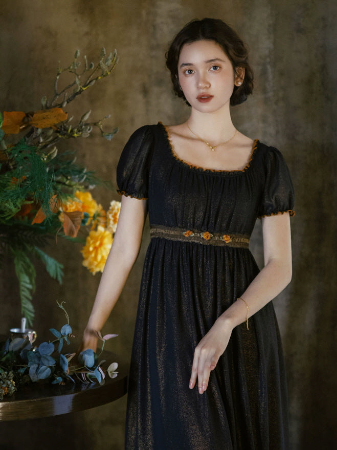 Black fairycore maxi dress with soft puff sleeves, fitted empire waist and flowing skirt in a moody floral setting