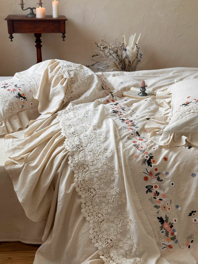 Fairycore inspired embroidered bedding with vintage floral accents, lace border, and ruffled pillow shams in soft cream tones