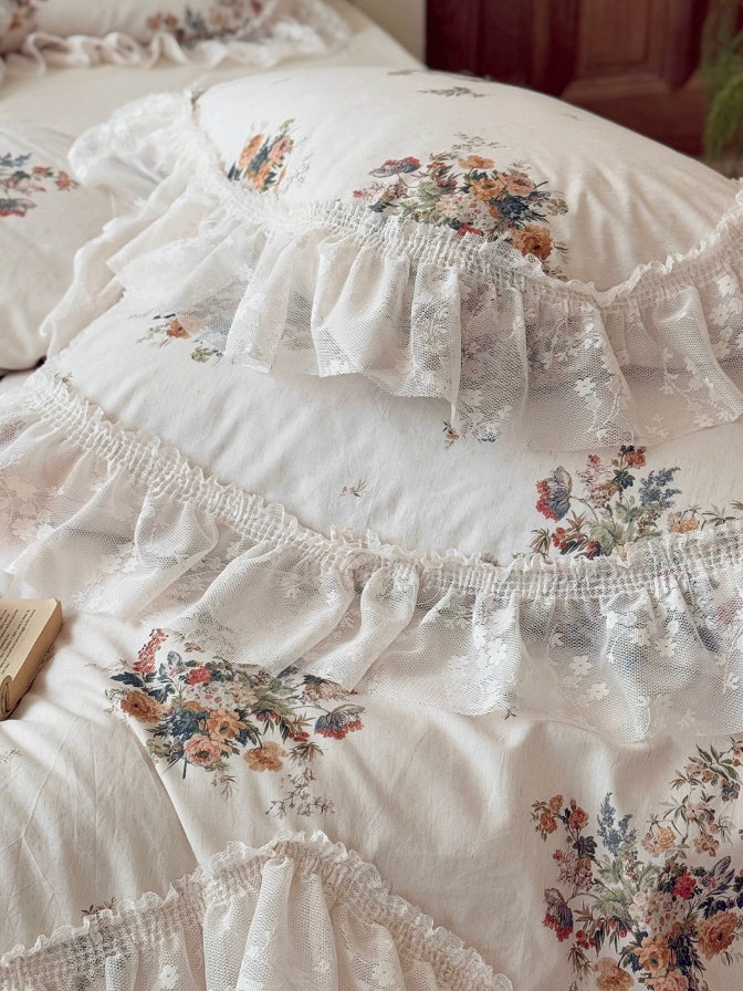 Vintage floral bedding set with layered lace ruffles, soft ivory fabric, and romantic cottagecore styling in a cozy bedroom