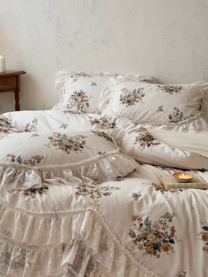 Romantic lace bedding with delicate bouquet print, sheer ruffled trim, and vintage inspired floral details in warm cream tones