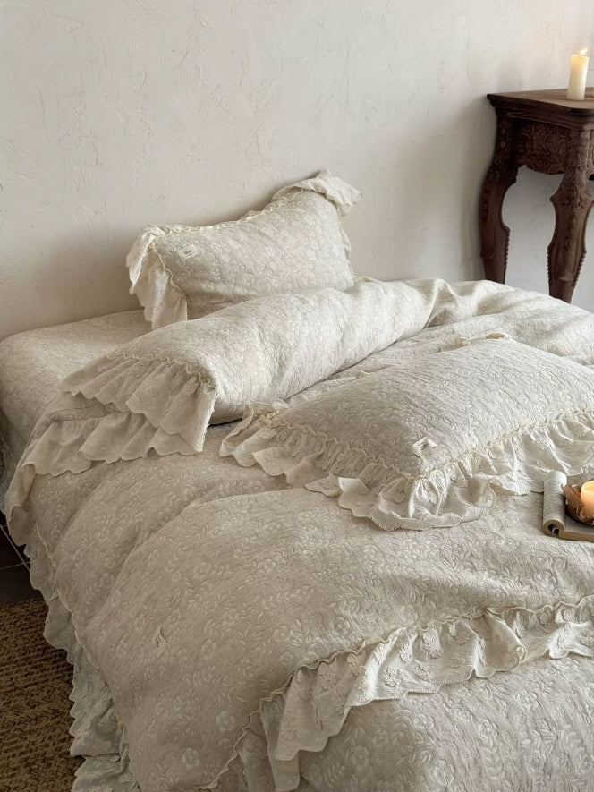 Romantic ivory bedding set styled with floral texture, soft gathers, and feminine lace ruffles