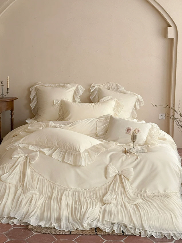 Ivory luxury ruffle bedding set styled with soft bows and flowing pleated bed skirt details