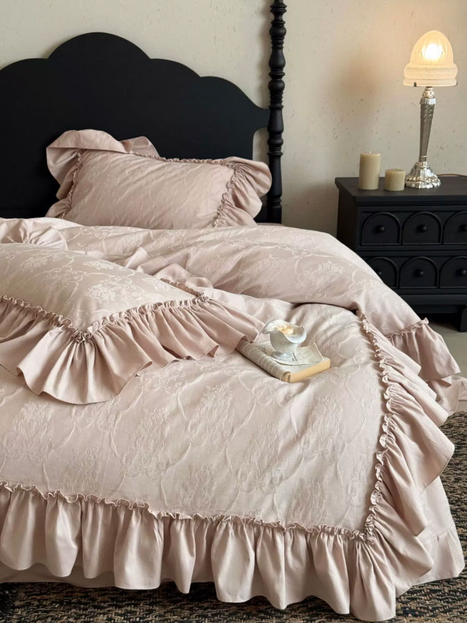 Soft dusty pink bedding with delicate floral jacquard pattern and gathered ruffle edges