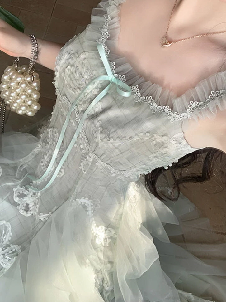 Close up of mint green lace fairy dress with ruffled neckline, delicate floral trim and satin ribbon bow