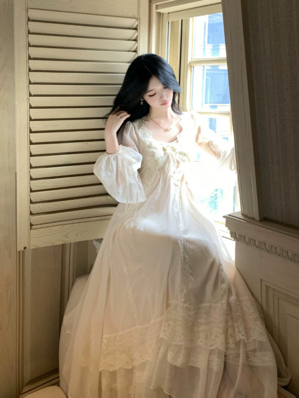 Ivory princesscore nightgown by the window with lace hem, voluminous sleeves and elegant flowing silhouette