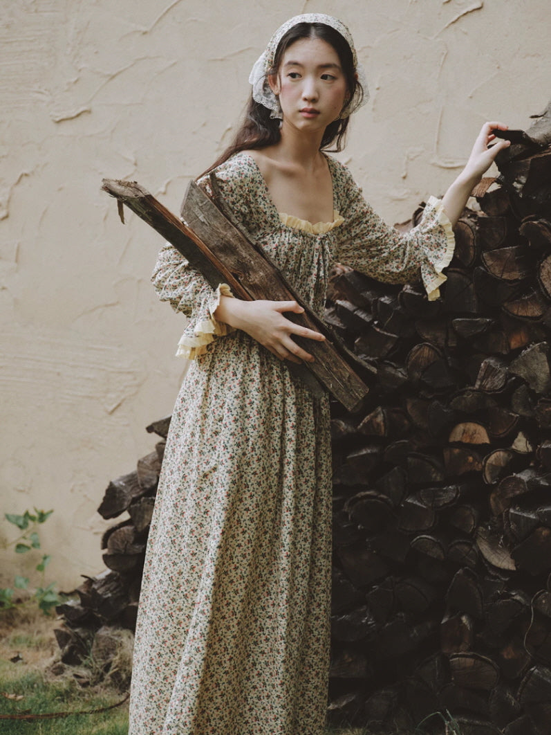 Cottagecore floral cotton nightgown with square neck, long sleeves and ruffled cuffs beside stacked firewood