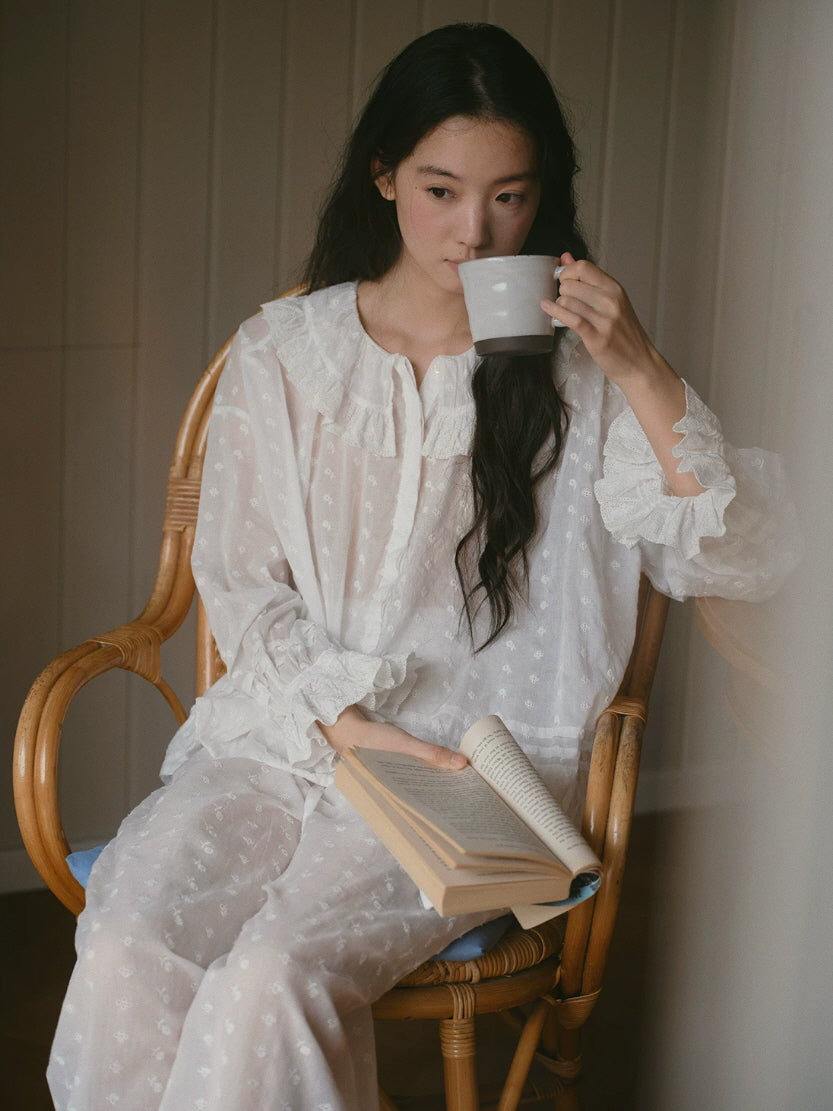 Cottagecore white sleepwear with floral eyelet embroidery and lace ruffles while reading indoors
