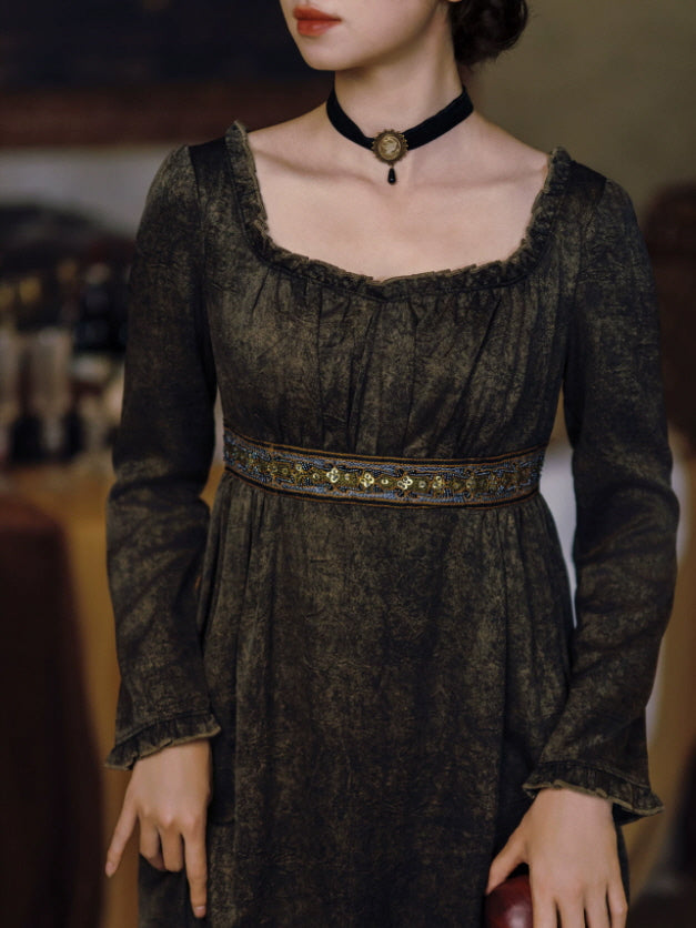 Close-up of dark vintage dress featuring square neckline, gathered bodice and ornate embroidered waist detail