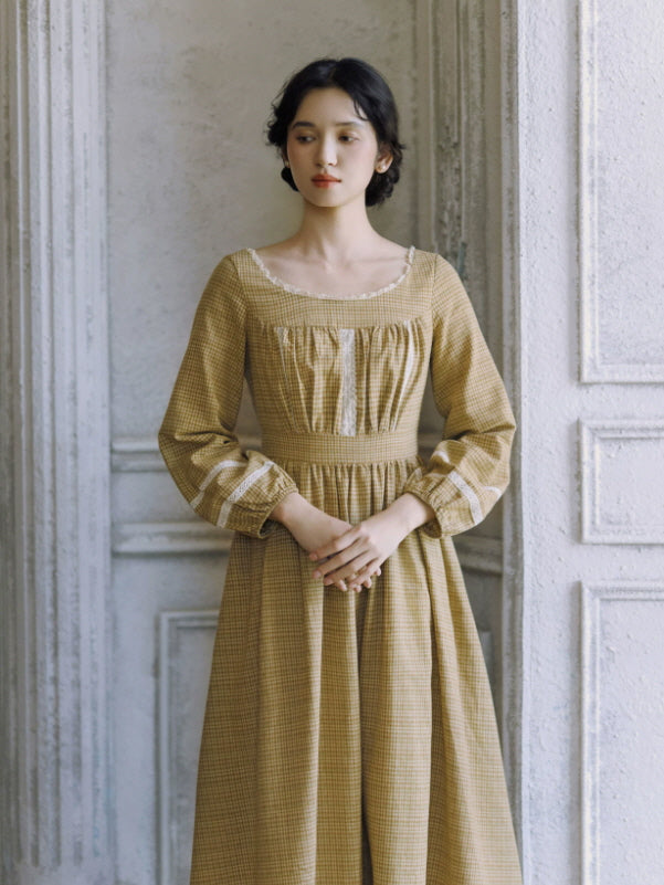 Vintage-inspired check maxi dress with square neckline, lace accents and softly gathered skirt by a window