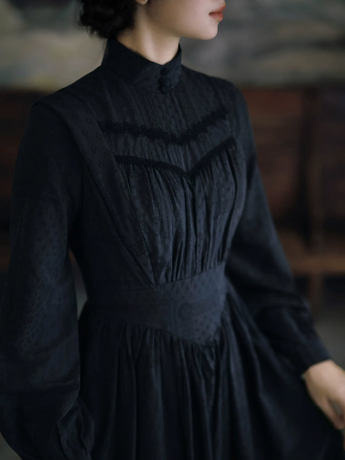 Close-up of black Victorian style dress featuring high collar, gathered front bodice and delicate trim details