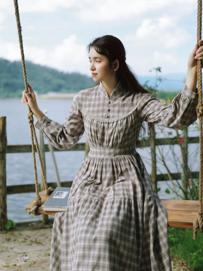 Gray cottagecore maxi dress with high neckline and lace detail styled on a wooden swing by the water