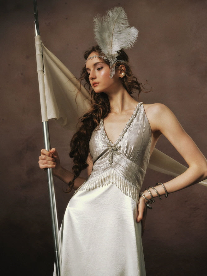 Close-up of vintage Art Deco styling with a pearl trimmed ivory satin dress, sparkling feather headpiece, and delicate beaded neckline.