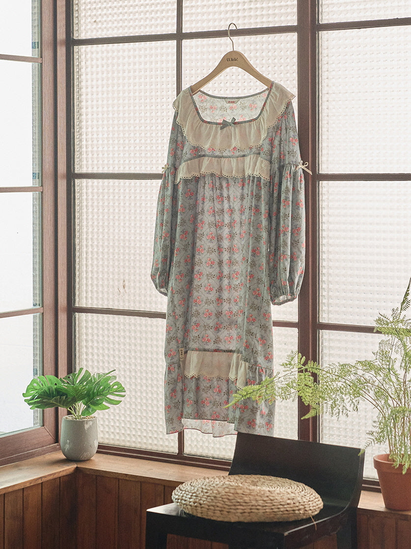 A vintage-inspired blue floral nightgown with puff sleeves and lace accents, hanging by a sunlit window to showcase its dreamy, fairytale aesthetic.