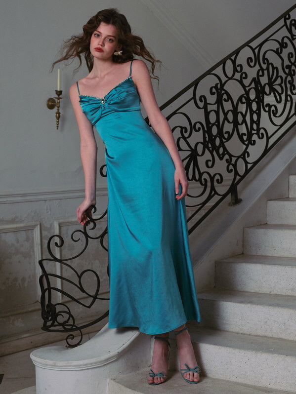 A woman standing gracefully on a grand staircase, wearing a turquoise satin dress with a ruched bodice and sparkling jewel detail — elegant evening fashion, vintage-inspired formal outfit, fairytale aesthetic.