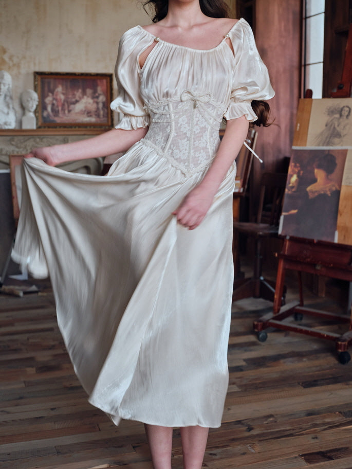 A woman walking across a wooden floor in an ivory satin dress with puff sleeves and a floral lace corset, holding the flowing skirt in a romantic, vintage-inspired interior.