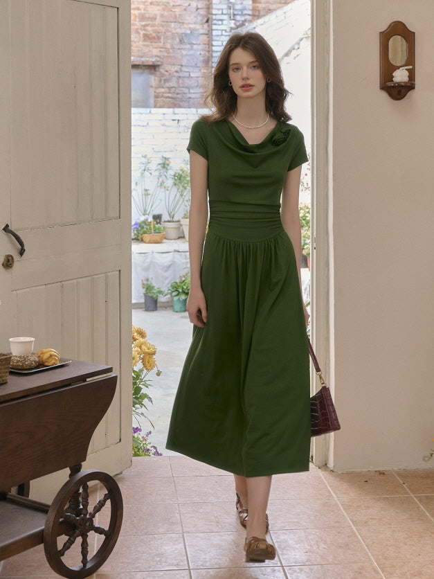 Woman wearing a forest green draped neckline dress with a gathered waist, walking through a cozy, vintage-inspired indoor garden setting. Elegant and natural fairytale mood.