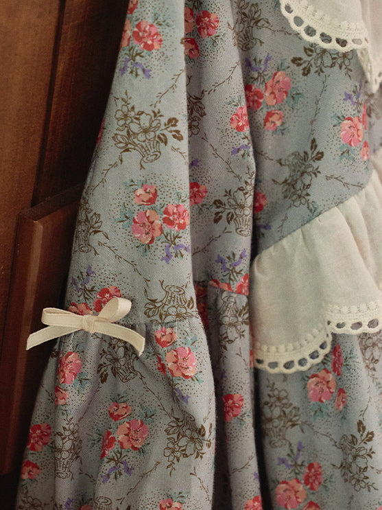 A close-up of the puff sleeve of a blue floral nightgown, featuring a delicate lace trim and a charming ribbon tie, exuding vintage elegance.