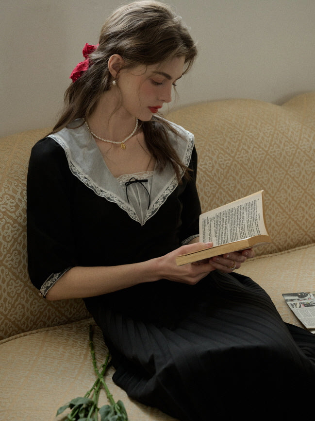 A dreamy and elegant retro black dress with delicate lace details, worn by a woman in a casual and aesthetic moment of quiet reading.