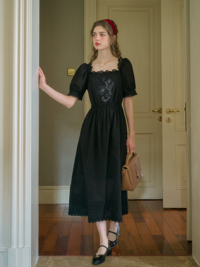 A young woman in a black embroidered puff sleeve dress and red headband, standing gracefully in a classic room with wooden floors, holding a brown handbag.