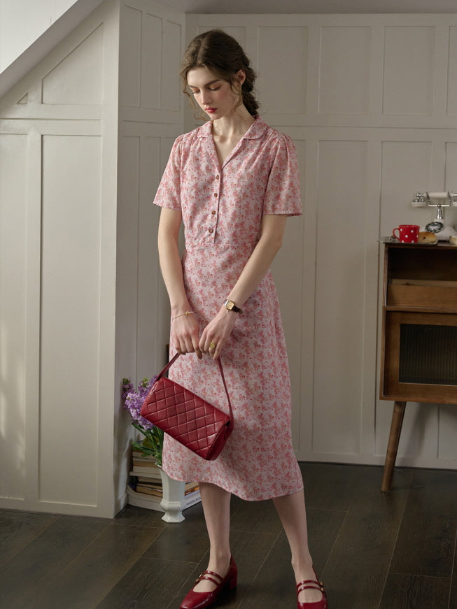 A woman in a casual cottagecore pink floral dress holding a red quilted handbag, styled for a soft and charming everyday look.