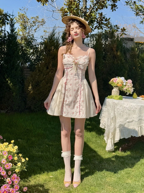 Coquette floral mini dress with lace trim and bow detail, styled with lace socks and a straw hat. Feminine, vintage-inspired summer look with a sweet, romantic garden scene.
