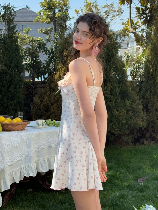 Side view of a floral knit dress with a flared hemline, styled with pastel pink ribbon detailing and ruffled lace trim for a romantic, vintage-inspired look.