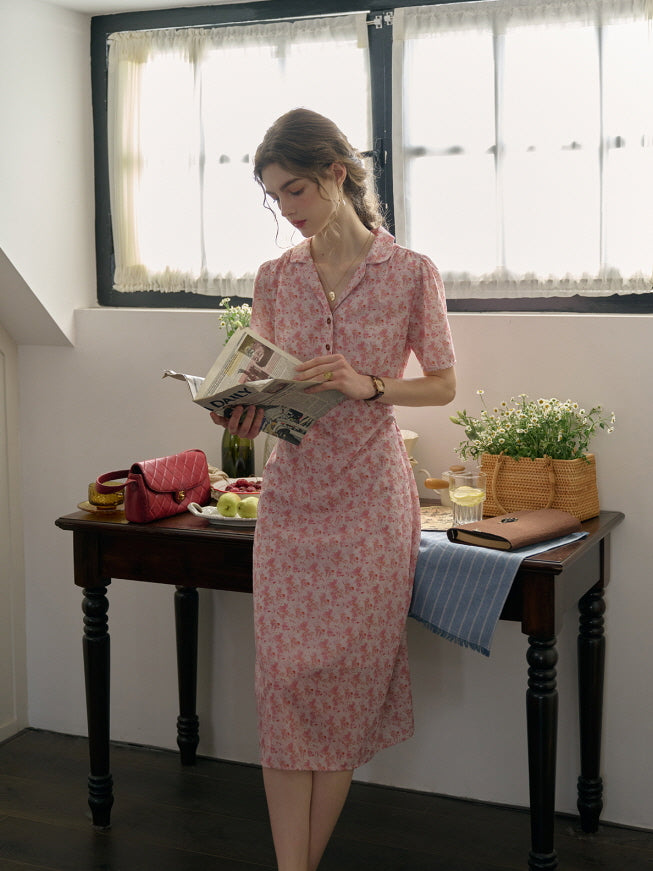 A romantic pink floral dress styled in a cottagecore and casual mood, as the woman enjoys a peaceful moment reading in a sunlit kitchen corner.