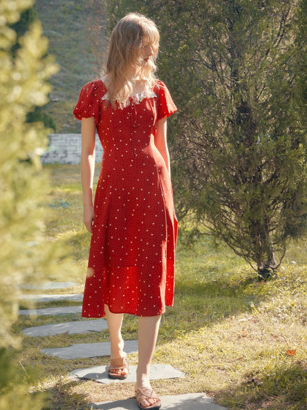A young woman in a red retro dress with lace detail, walking joyfully through a garden on a sunny summer day.