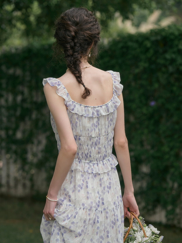 Back view of a woman with braided hair wearing a cottagecore floral outfit, featuring a ruffled sleeveless dress with a soft aesthetic against a lush green background.