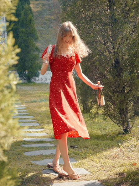 A romantic red dress with puff sleeves and lace accents, styled for summer walks in a peaceful garden path.