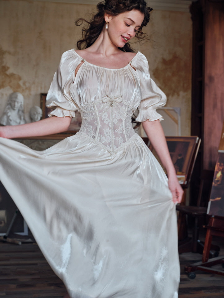 A woman dancing in a softly lit room while wearing a shimmery ivory dress with puff sleeves and a lace corset bodice, styled in a romantic vintage aesthetic with a painterly backdrop.