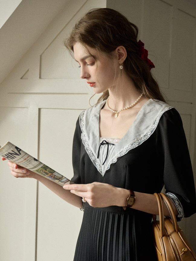 A woman in a retro-inspired black dress with a wide lace-trimmed collar, styled for a casual and aesthetic look with fairytale charm.