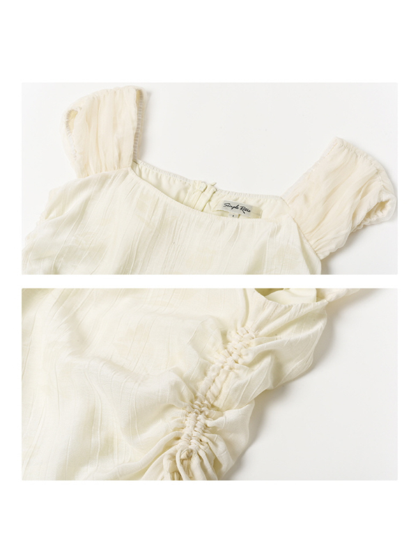 Close-up of a light ivory dress showing the softly gathered cap sleeves and ruched side seams, emphasizing the lightweight texture and romantic craftsmanship.