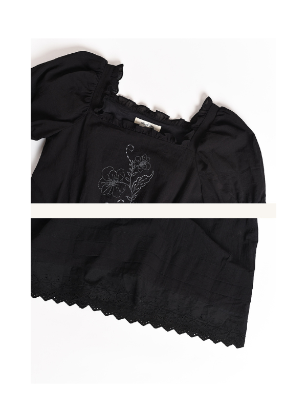 Retro vintage-inspired black dress showcasing floral embroidery on the chest and delicate scalloped hemline details.