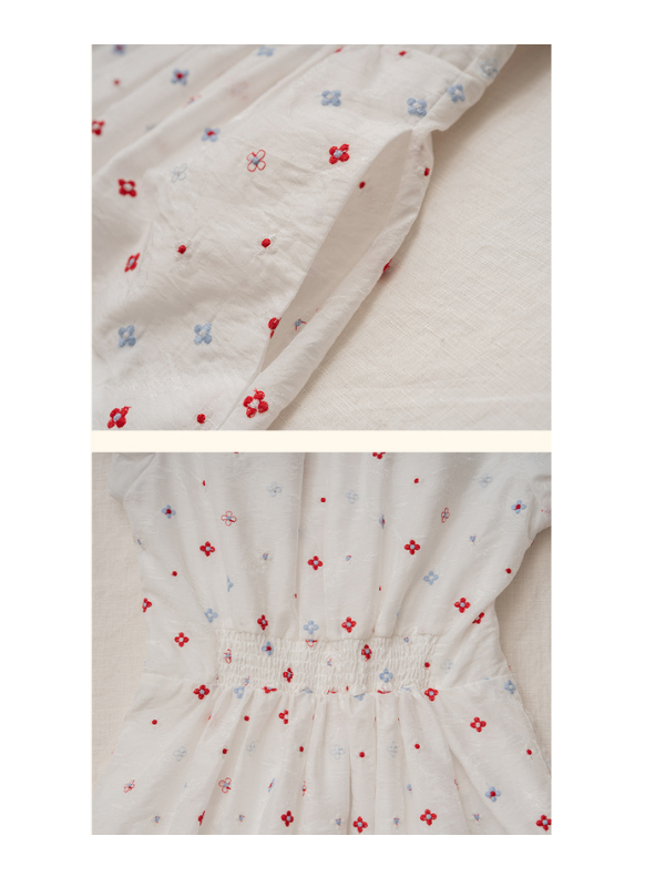 Close-up of two dresses hanging side by side — a white floral embroidered dress with red and blue flower patterns and a lavender floral print dress. The detailed embroidery showcases delicate, cottagecore-inspired designs.