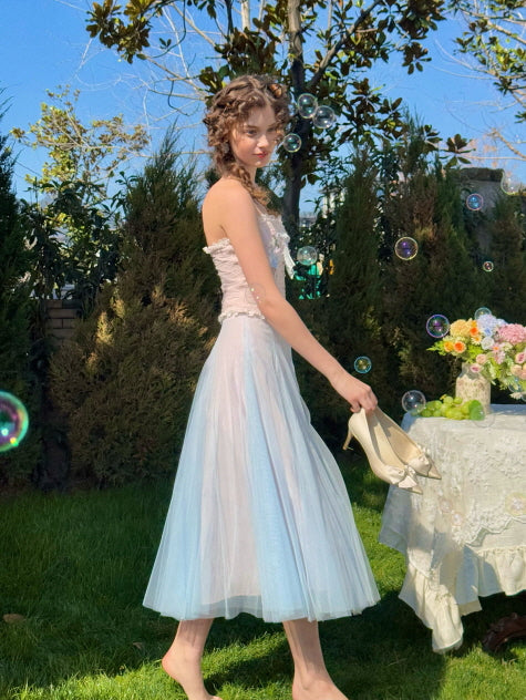 Pastel blue corset dress with floral appliqué and tulle skirt, worn by a woman walking barefoot through a garden with bubbles – dreamy fairytale fashion look