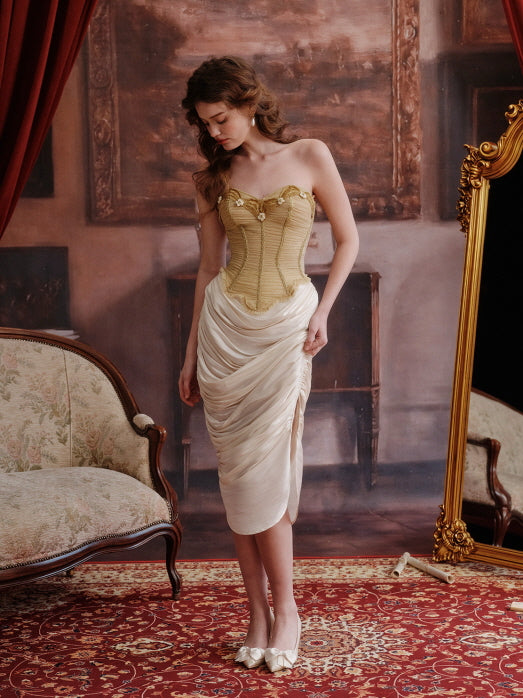 Full-length view of a romantic gold corset and ivory draped skirt set, styled in an elegant fairytale-inspired room with vintage furniture and a red carpet for a regal mood.