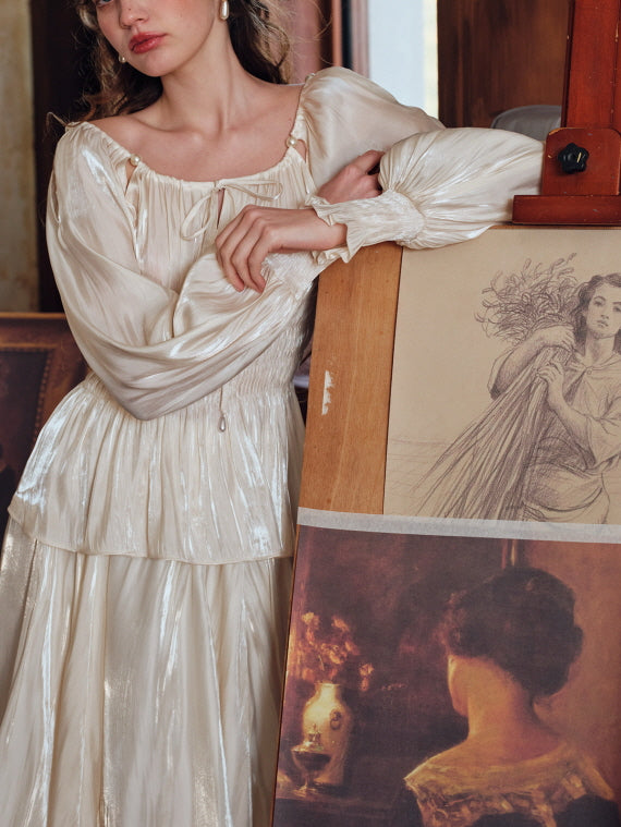 Elegant soft cream blouse with long poet sleeves and ribbon neckline, styled with a pleated skirt in a cottagecore-inspired vintage drawing room setting.