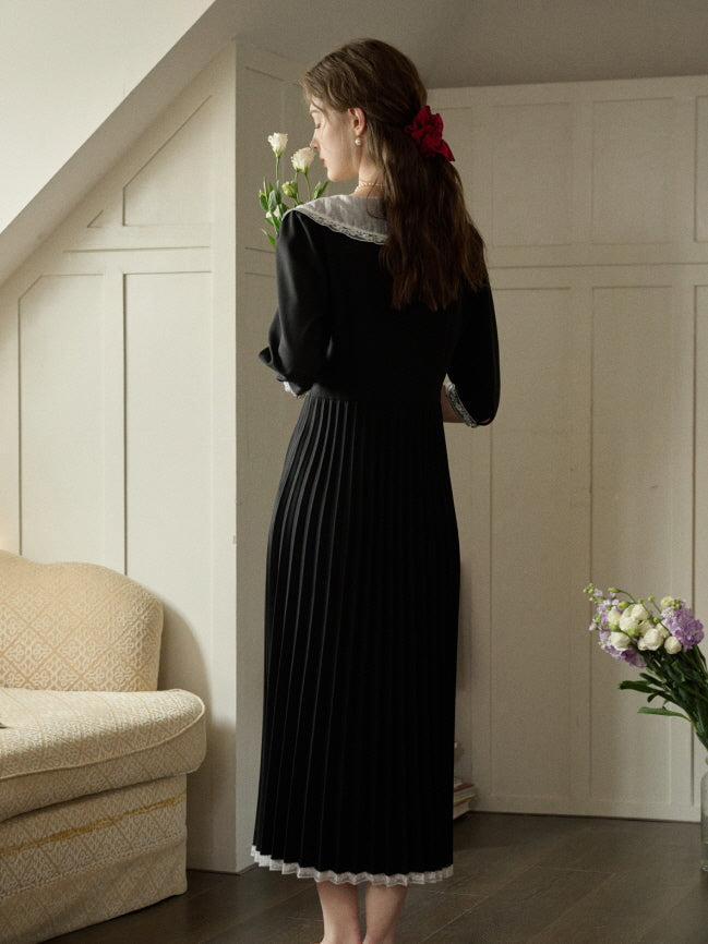 A romantic fairytale-inspired outfit featuring a pleated black dress with lace details, captured from behind as the woman holds white flowers in a vintage interior.