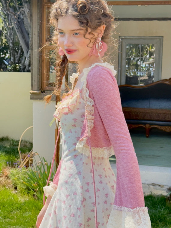 Side view of a model wearing a pink cardigan with lace trim over a floral waffle-textured dress, evoking a fairytale-inspired cottagecore aesthetic.