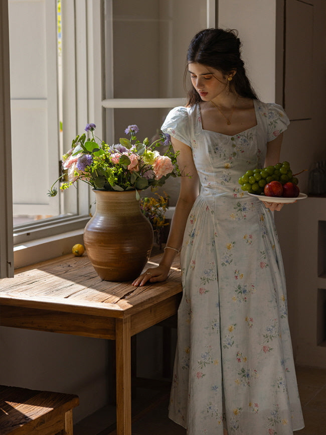 Whimsical floral dress with a flowy silhouette and sweetheart neckline, styled with a vintage ceramic vase filled with pastel flowers, creating a dreamy, cottagecore kitchen scene bathed in warm, natural light.