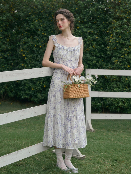 Woman dressed in a romantic cottagecore floral dress, holding a wicker basket filled with white flowers, posing by a white wooden fence – vintage fashion aesthetic.