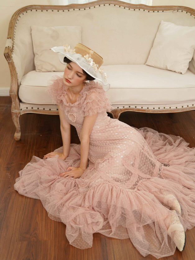 Model kneels gracefully in a vintage pink tulle dress with ruffled sleeves and pearl heart detail, evoking a soft princesscore atmosphere.