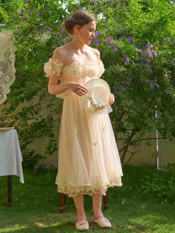 The model stands in a blooming garden wearing a romantic ivory skirt with lace and ribbon bow details, styled for a soft fairy princess look.