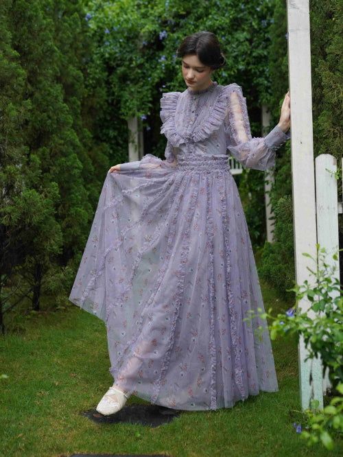 Wearing a vintage-inspired sheer lavender dress, the model stands beneath a garden arch, evoking a soft and romantic fairytale scene.